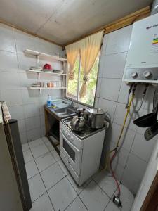 a small kitchen with a stove and a sink at Ancoa Lodge in Linares