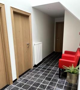 een lege gang met een rode stoel en een deur bij Gastenkamer BLOOM in Brugge