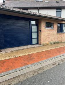 een bakstenen huis met twee garagedeuren en een stoep bij Gastenkamer BLOOM in Brugge