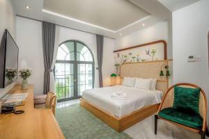 Misaki HCM Airport Hotel في مدينة هوشي منه: غرفة نوم بسرير كبير وكرسي أخضر