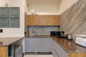 una cocina con encimeras de mármol y armarios de madera en Sunworld Arista, en Noida