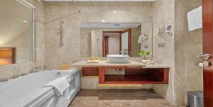 a bathroom with a tub and a sink and a mirror at Sandals Stay Hotel in Da Nang +38 photos