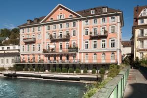 een groot roze gebouw naast een rivier bij Limmathof Baden - Historisches Haus & Spa in Baden