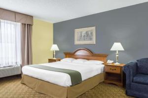 a hotel room with a large bed and a chair at Days Inn by Wyndham Selma in Selma +17 photos