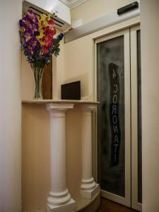 a vase of flowers on a shelf next to a door at Hotel 4 Coronati in Rome