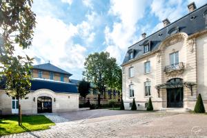 un grand bâtiment blanc avec un toit bleu dans l'établissement Les Suites du Champagne de Venoge, à Épernay