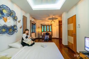 a woman sitting on a bed in a room at Evergreen2 เอเวอร์กรีนทู in Ban Pok Nai