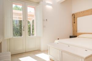 a white bedroom with a bed and a window at Masseria Mongiò dell'Elefante in Otranto