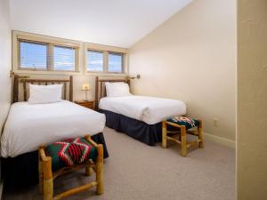two beds in a room with two chairs and two windows at RMR: Snow Ridge 4 Condo in Teton Village in Teton Village +17 photos