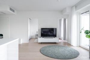 a white living room with a tv and a rug at New apartment with sauna, lake and beach in Tampere