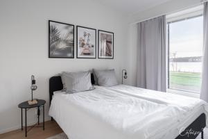 a bedroom with a white bed with four pictures on the wall at New apartment with sauna, lake and beach in Tampere