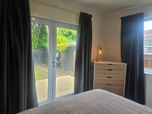 a bedroom with a bed and a sliding glass door at Modern, House in central Palmerston North in Palmerston North
