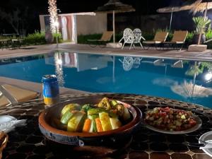 a bowl of food on a table next to a pool at Riad Mhidou Marrakech in Marrakesh