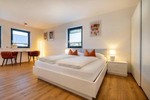 a white bedroom with a large white bed and a desk at S Apartment in Flachau
