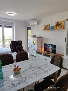 un soggiorno con tavolo, sedie e TV di Sara apart a Pojate