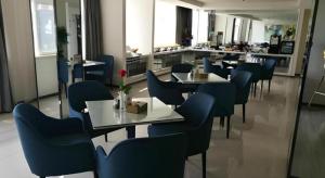 een restaurant met tafels en blauwe stoelen in een kamer bij Jinjiang Inn Select Taizhou Jiangyan Coach Terminal in Magou