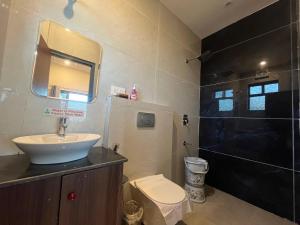 a bathroom with a sink and a toilet and a mirror at 11 Gaon Homestay Lansdowne in Lansdowne