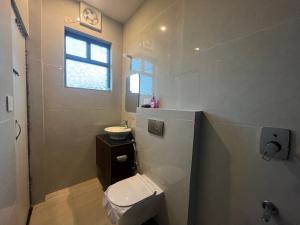 a bathroom with a toilet and a sink and a window at 11 Gaon Homestay Lansdowne in Lansdowne