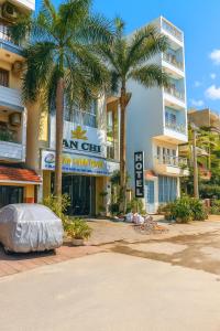 a hotel with palm trees in front of a building at Khách Sạn An Chi in Ho Chi Minh City +26 photos