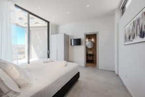 Un dormitorio blanco con una cama y una ventana grande. en Dione Villa, en Sellía 46 fotos más