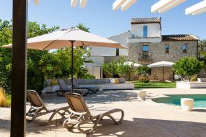 une terrasse avec des chaises et un parasol ainsi qu'une piscine dans l'établissement 18Th Century Farmhouse In Racalmuto Countryside, à Grotte