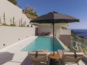 una piscina con sombrilla y sillas junto a una casa en Zeus Villa, en Sellía