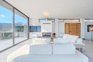 Una sala de estar con muebles blancos y grandes ventanales. en Zeus Villa, en Sellía
