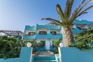 a blue building with a palm tree in front of it at Alpha Studios in Arkasa