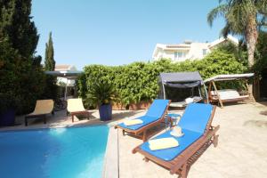 a pool with two lounge chairs and a gazebo at Helene Villa in Protaras