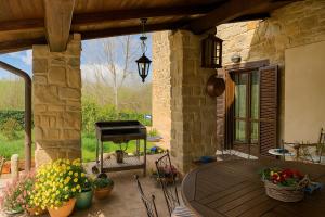 a patio with a table and a grill and flowers at VILLA NASCA - Ville Carborello in Castelraimondo