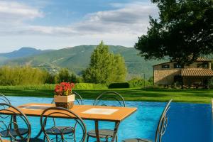 a wooden table and chairs next to a pool at VILLA NASCA - Ville Carborello in Castelraimondo