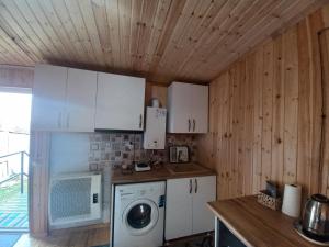 a kitchen with white cabinets and a washing machine at Sesili's apartment in Stepantsminda