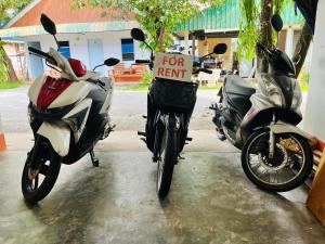 two motorcycles parked next to each other with a for rent sign at Montra Guesthouse in Ranong +1 photo