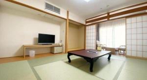 een woonkamer met een salontafel en een tv bij Sunshine Shirako New in Shirako