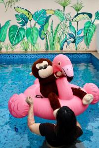 une personne dans une piscine avec un ours en peluche sur un matelas gonflable dans l'établissement 2BHk Peacock in North Goa, à Porvorim