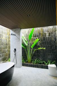 La salle de bains est pourvue d'une baignoire et d'une plante. dans l'établissement Biển tôm ốc homestay hồ bơi & BBQ garden, à Xóm Bình Nguyên