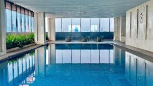 a swimming pool with chairs in a building with windows at ibis Styles Jakarta Tanah Abang in Jakarta