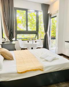 een slaapkamer met een groot wit bed en een bureau bij Levi Living in Da Nang