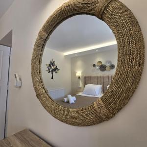 a bedroom with a large rattan mirror on the wall at Villa Bacchus Kassiopi Corfu in Kassiopi