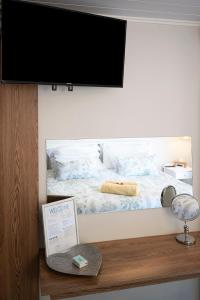 a flat screen tv on a wall with a bed at Stylish OceanBreeze 50 Central Mossel Bay in Mossel Bay