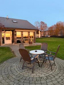 um pátio com três cadeiras e uma mesa e um edifício em Add Story Guest House em Rēzekne