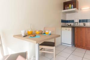 a kitchen with a wooden table with oranges on it at Comfort Aparthotel Nantes La Beaujoire in Nantes