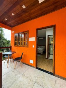 イーリャ・グランデにあるSuítes Refúgioのパティオにテーブルと椅子が置かれたオレンジ色の壁