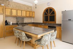 a kitchen with a large wooden table and a refrigerator at Villa Douira avec piscine, proche d'Essaouira in Essaouira
