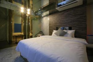 um quarto com uma grande cama branca e uma parede de tijolos em The Ace Hotel em Seul