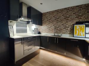 a kitchen with black cabinets and a brick wall at Modern Riverside Flat in central Reading, Free Parking, Fast WiFi, Near Station in Reading