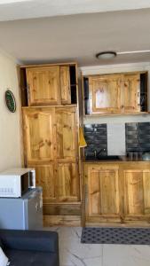 a kitchen with wooden cabinets and a microwave at Le Studio Marin in Bouéni +8 photos