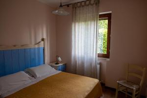 a bedroom with a bed and a window and a chair at Agriturismo Roccagelli in Vallo di Nera