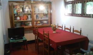 a dining room with a red table with chairs and a television at Vilage Home in Polonnaruwa
