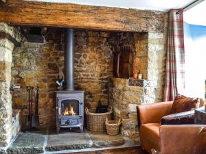a stone wall with a stove in a living room at Juniper Cottage in Hook Norton